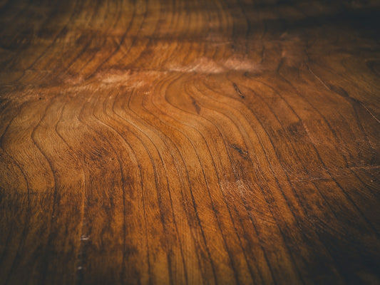A close-up of a polished wooden surface with visible dark brown grain patterns