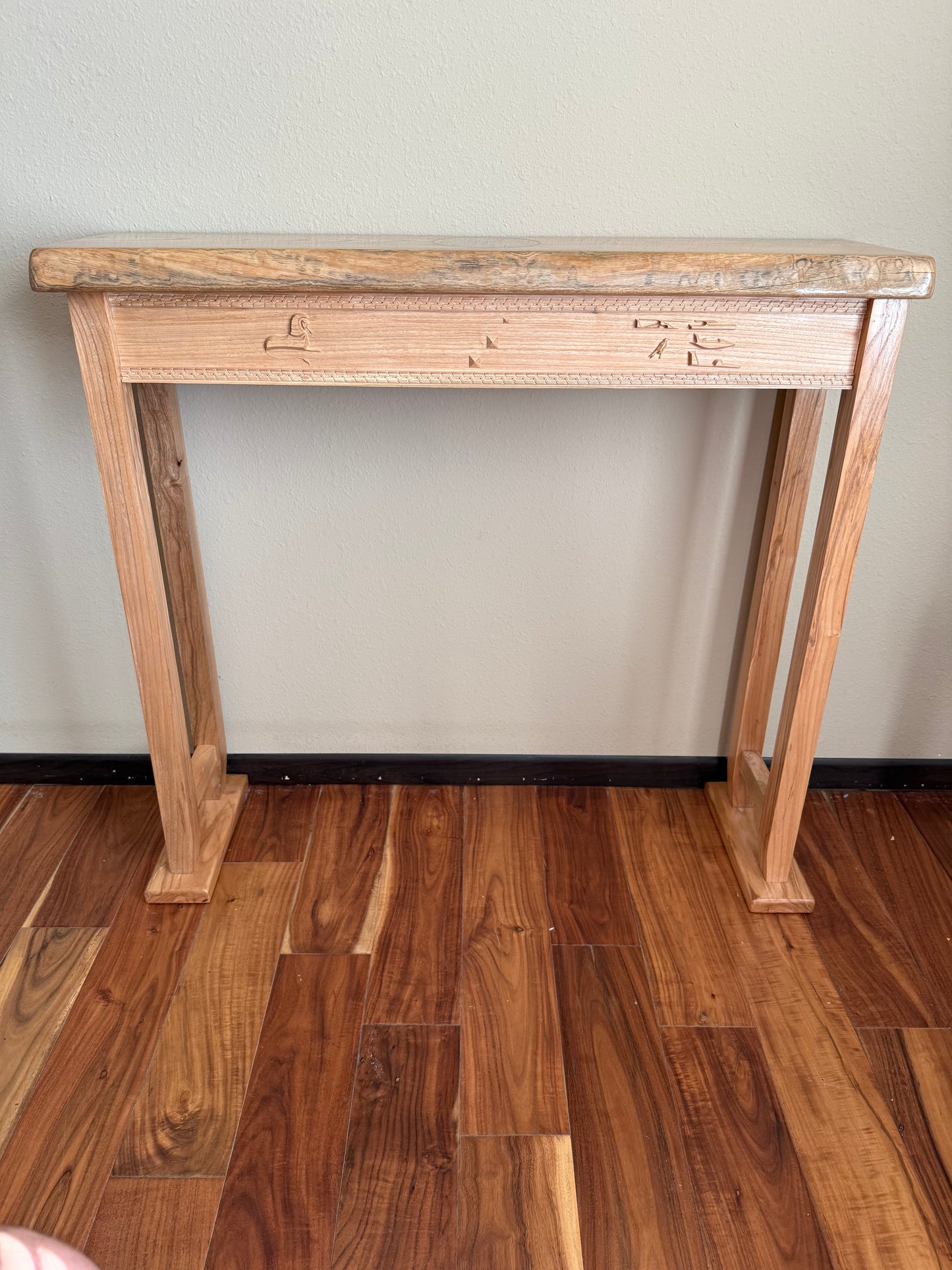Wooden console table against a plain wall on a wooden floor