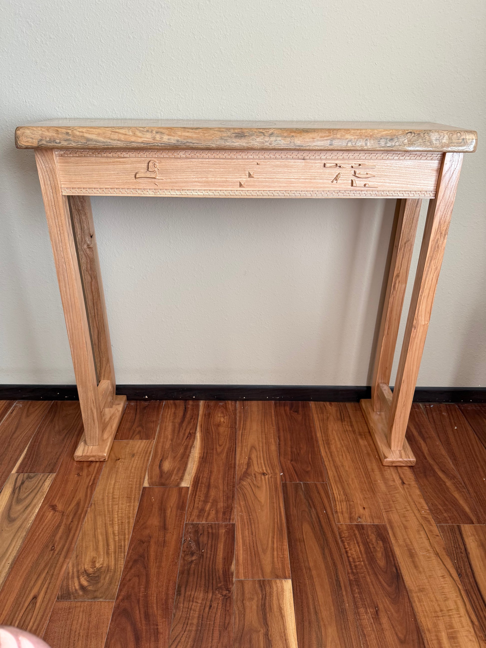 Wooden console table against a plain wall on a wooden floor