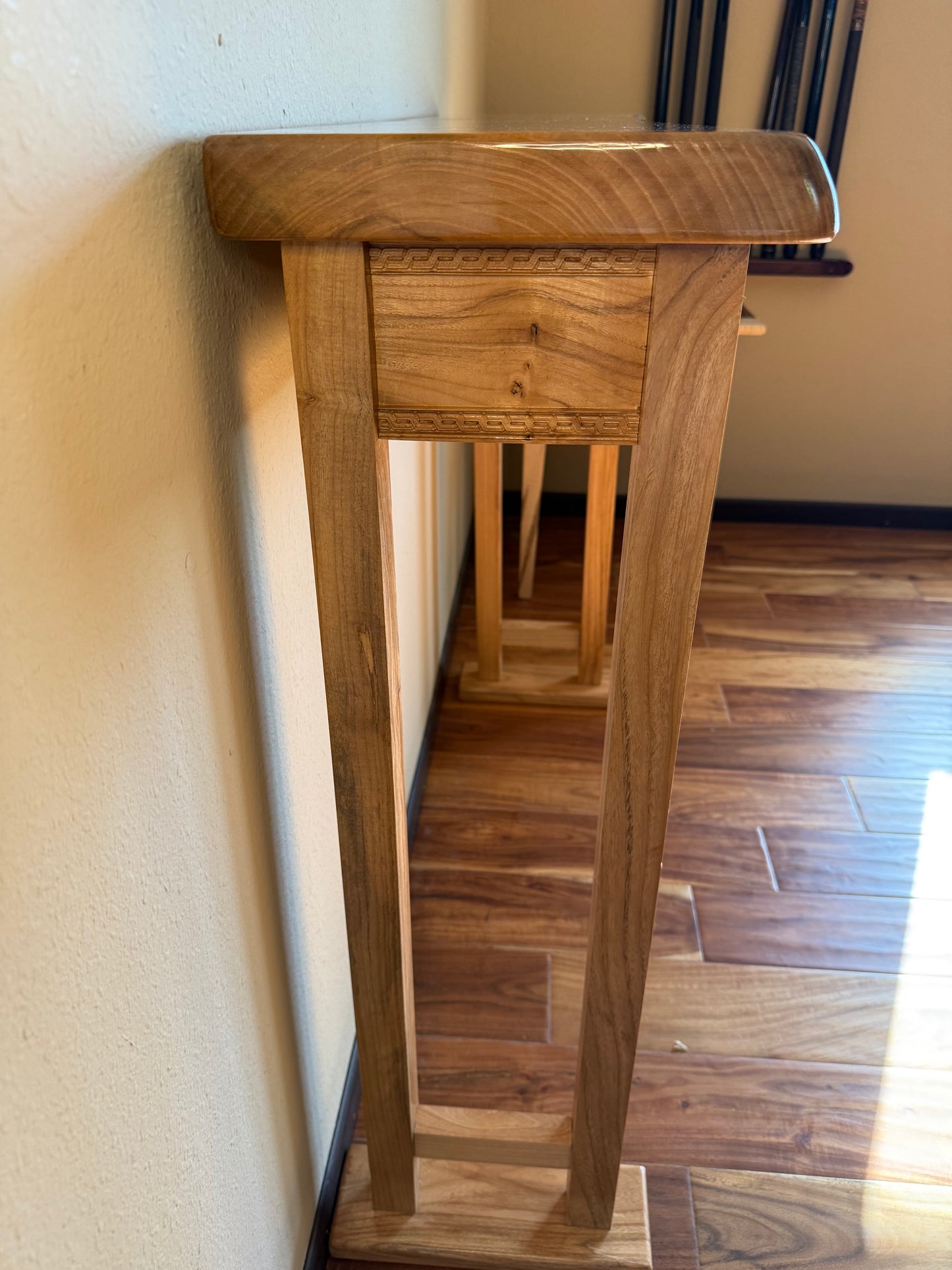 Wooden console table against a wall in a room with wooden flooring.